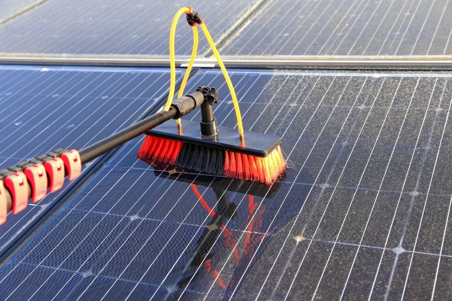 solar panels on a roof being cleaned by a pressure washing brush 