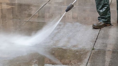 patio in garden being pressure washed with green shrubs in the background by homeuplift