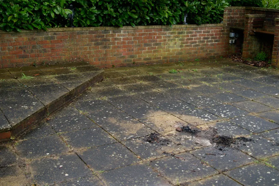 Heavy contaminated patio with a briwk wall and a bush 